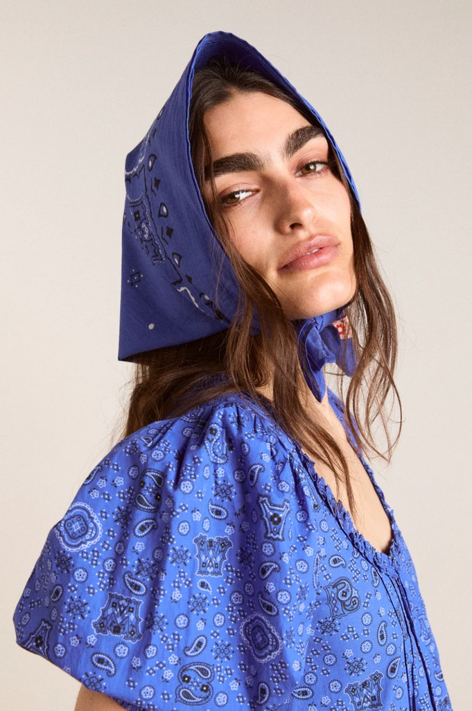 A model for Damson Madder poses in a blue bandana and matching dress