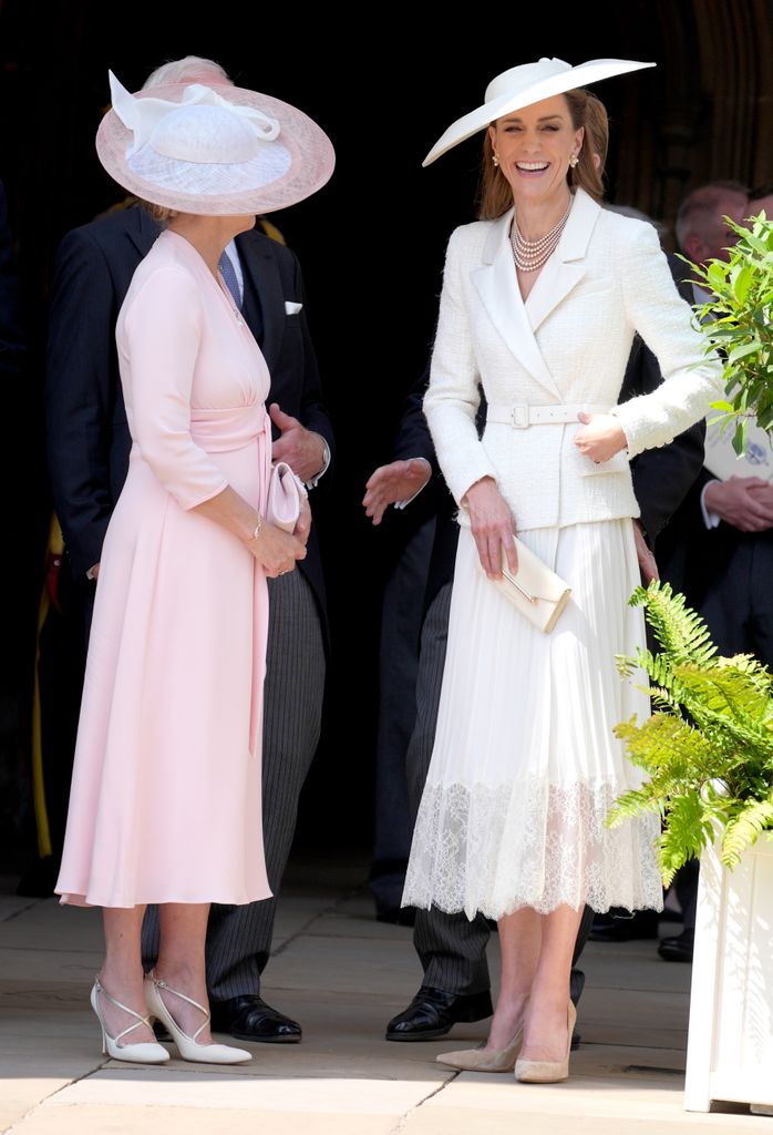 two women laughing and chatting in formal attire