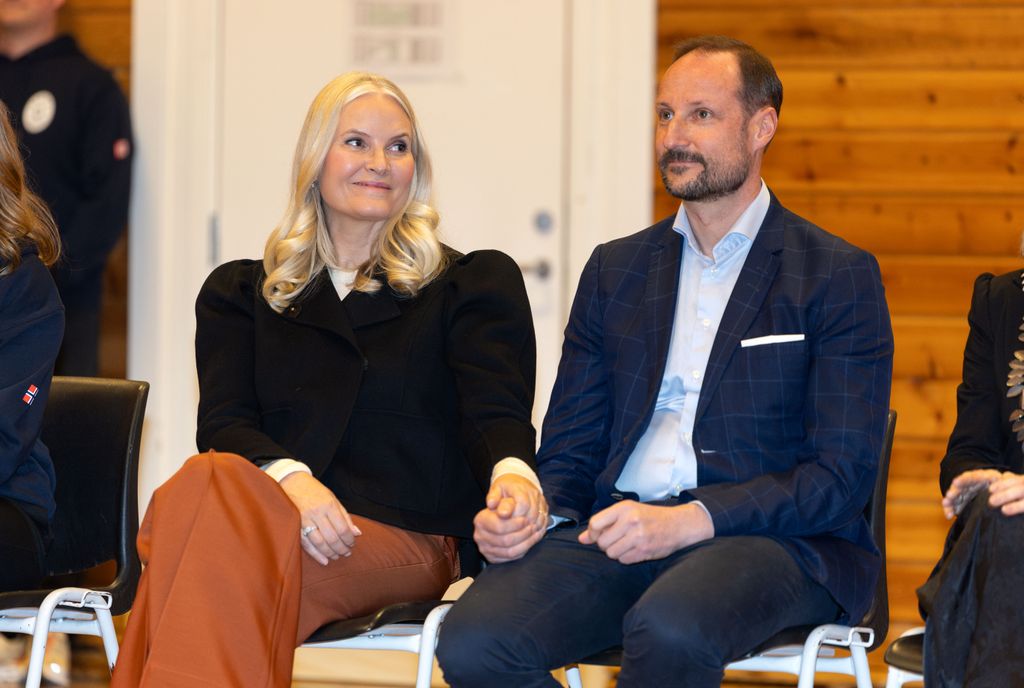 Mette-Marit and Haakon holding hands as they visit school band